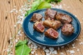 Medium Rare Fried Diced Marinated Beef on Blue Ceramic Plate on Wood Panel with Sea Salt and Vegetable Decorated