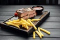 Medium rare grilled Beef steak Ribeye with roasted potato wedges and tomatoes on cutting board on wooden background Royalty Free Stock Photo