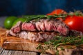 Medium rare grilled beef steak ribeye with rosemary and tomatoes on wooden cutting board on dark blue background. Appetizing image Royalty Free Stock Photo