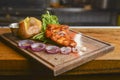 Medium rare grilled Beef steak with roasted potato wedges and green salad on cutting board on wooden background. Royalty Free Stock Photo