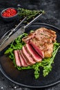 Medium rare sliced grilled striploin beef steak or new york steak. Black background. Top view