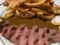 Medium Rare Steak Dinner With French Fries and Brown Sauce Royalty Free Stock Photo