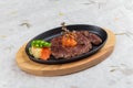 medium rare wagyu steak topping with mince carrot on hot plate and wooden plate served with potato salad on washi. Royalty Free Stock Photo