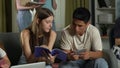 Medium shot of a boy and a girl sitting on a couch in a group of teens, young people, friends, studying, preparing for Royalty Free Stock Photo