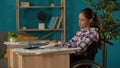 Medium shot capturing a disabled young woman on a wheelchair working in her home office. Young architect looking through