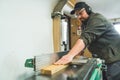 Medium shot of a carpenter using a table saw to cut a plank of wood while working in his woodworking studio Royalty Free Stock Photo