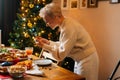 Medium shot of cheerful young woman taking photo or making video of beautiful Christmas dinner table on mobile phone. Royalty Free Stock Photo