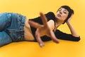 Medium shot. Female model lying on her side with an arm reaching forward and another supporting her hand