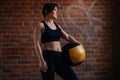 Medium shot of fitness young athletic woman with strong beautiful body in black sportswear posing with heavy medicine Royalty Free Stock Photo