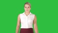 Formaly dressed young woman walking to the camera on a green screen, chroma key.