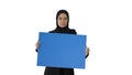 Serious Arab woman in hijab holding blank blue poster and lookin Royalty Free Stock Photo