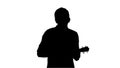 Silhouette Young man playing ukulele and signing while walking a Royalty Free Stock Photo