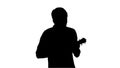 Silhouette Young man playing ukulele and signing while walking. Royalty Free Stock Photo