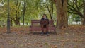 Medium shot of handsome young man working on laptop computer sitting outdoors in park. Male looking away thoughtfully Royalty Free Stock Photo