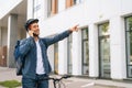 Medium shot of joyful handsome delivery man with thermal backpack talking on mobile phone, sees customer and marks Royalty Free Stock Photo