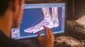 Medium shot of a learner participating in a virtual podiatric surgery simulation on a computer emphasizing digital skill Royalty Free Stock Photo