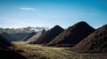 Medium shot of openair composting facility with large piles of organic waste undergoing natural decomposition under Royalty Free Stock Photo