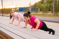 Medium shot of personal training from athletic lady for obese female with big abdomen outdoor in cloudy summer evening.