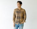 Medium shot portrait of a casual Asian handsome man with cute smiling in a light brown plaid shirt and blue jeans with one hand in Royalty Free Stock Photo