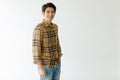 Medium shot portrait of a casual Asian handsome man with cute smiling in a light brown plaid shirt and blue jeans with one hand in Royalty Free Stock Photo