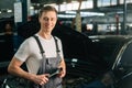 Medium shot portrait of cheerful handsome young mechanic male wearing uniform holding special key ratchet wrench