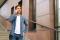 Medium shot portrait of confident handsome young man talking on mobile phone standing on stairs of modern office Royalty Free Stock Photo