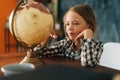 Medium shot portrait of happy curious child girl spinning small globe with interest, looking at countries of world. Royalty Free Stock Photo