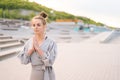 Medium shot portrait of meditative Caucasian young woman practicing yoga performing namaste pose outside in city park. Royalty Free Stock Photo
