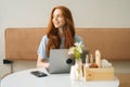 Medium shot portrait of smiling young woman working typing using on laptop computer sitting at table in cozy cafe Royalty Free Stock Photo