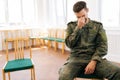 Medium shot portrait of unhappy young soldier male in camouflage uniform with PTSD crying sitting in circle during group Royalty Free Stock Photo