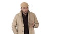 A positive bearded male dressed in a trench coat walking and talking on white background.