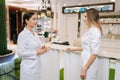 Medium shot of professional female doctor and young nurse talking, standing in clinic lobby. Physicians colleagues Royalty Free Stock Photo