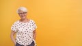 Medium shot of senior woman with gray hair and glasses isolated on the orange background