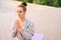 Medium shot of serene Caucasian young woman practicing yoga performing namaste pose with closed eyes outside in city Royalty Free Stock Photo