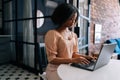 Medium shot of serious African female student typing on notebook keyboard studying working online. Black business woman Royalty Free Stock Photo