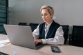 Medium shot of serious professional mature business woman using typing on laptop computer sitting at workplace desk. Royalty Free Stock Photo