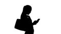 Silhouette Beautiful young woman using a mobile phone walking and holding shopping bags. Royalty Free Stock Photo