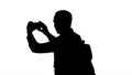 Silhouette Handsome young man carrying backpack and taking a picture of himself. Royalty Free Stock Photo