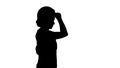 Silhouette Young happy attractive woman in construction uniform putting yellow construction hat on while walking. Royalty Free Stock Photo