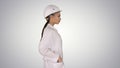 Woman in white robe putting hard hat on while walking on gradient background. Royalty Free Stock Photo
