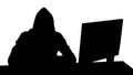 Silhouette Hooded hacker using laptop and smartphone.