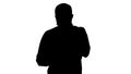 Silhouette Sad young man walking and looking at his mobile phone with his hand on his face. Royalty Free Stock Photo