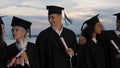 Mixed races happy students in classic graduation mantles and aca