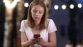 Upsetting news. Teen girl messaging with her phone in a cafe in the evening.