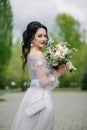 Medium shot of smiling bridesmaid with bridal bouquet and wearing fashionable, elegant dress