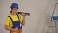 Medium shot of a smiling young construction worker wearing a tool belt, holding a construction water level on his Royalty Free Stock Photo