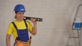 Medium shot of a smiling young construction worker wearing a tool belt, holding a construction water level on his Royalty Free Stock Photo