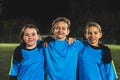 medium shot of three little girls wearing soccer blue uniforms and posing together, evening practice, teamsport concept