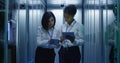 Two women are working in a data center with rows of server racks