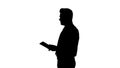 Silhouette Elegant young businessman using tablet while walking.